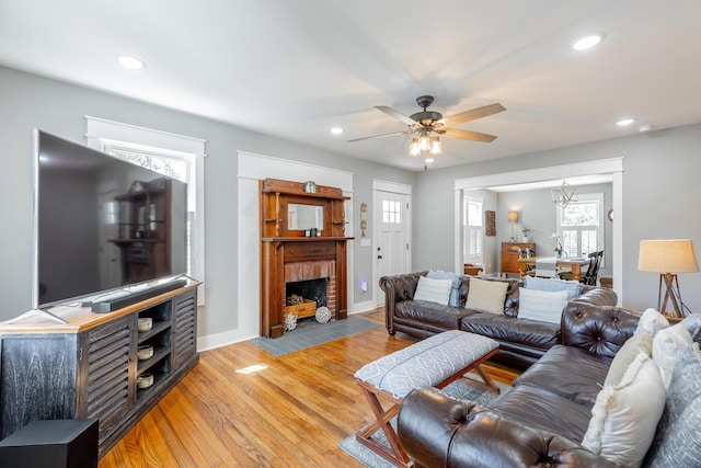living room with recessed lighting, a ceiling fan, baseboards, light wood-style floors, and a brick fireplace