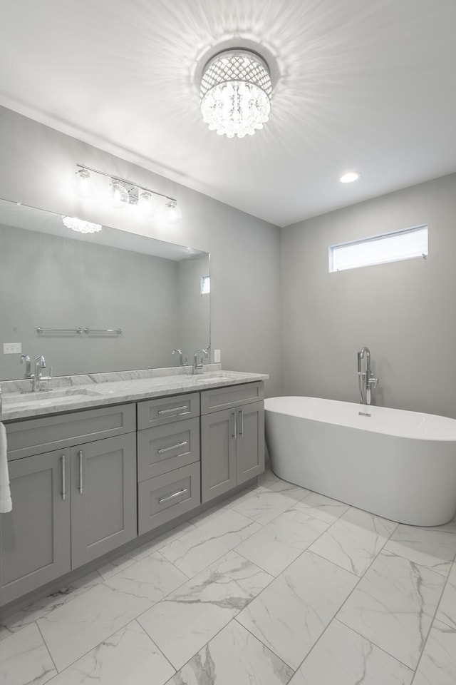 bathroom featuring double vanity, marble finish floor, a freestanding bath, and a sink
