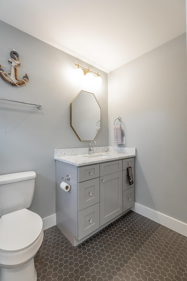 half bathroom featuring toilet, baseboards, and vanity