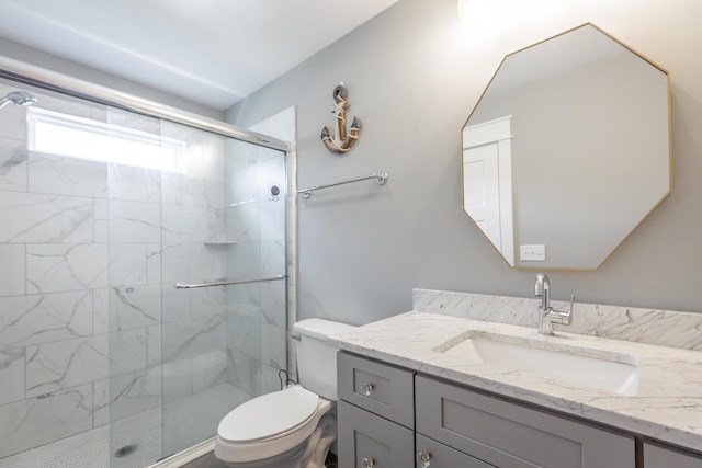 bathroom featuring toilet, a marble finish shower, and vanity