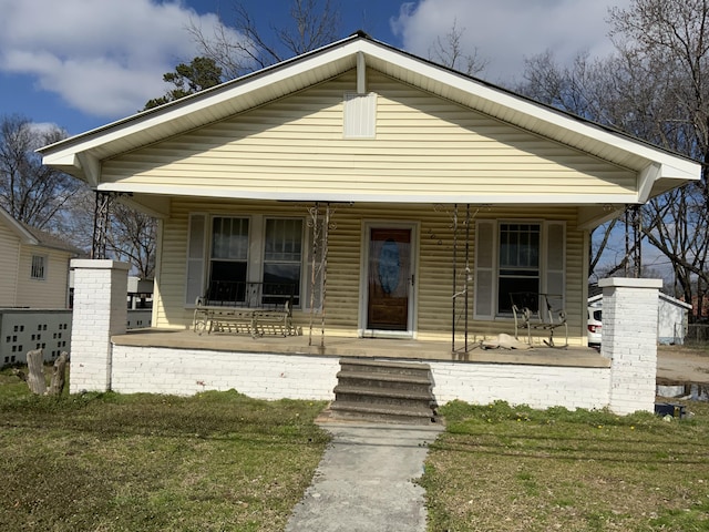 bungalow-style home featuring covered porch and a front yard