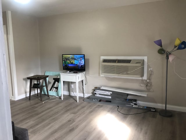 interior space with baseboards, a wall unit AC, and wood finished floors