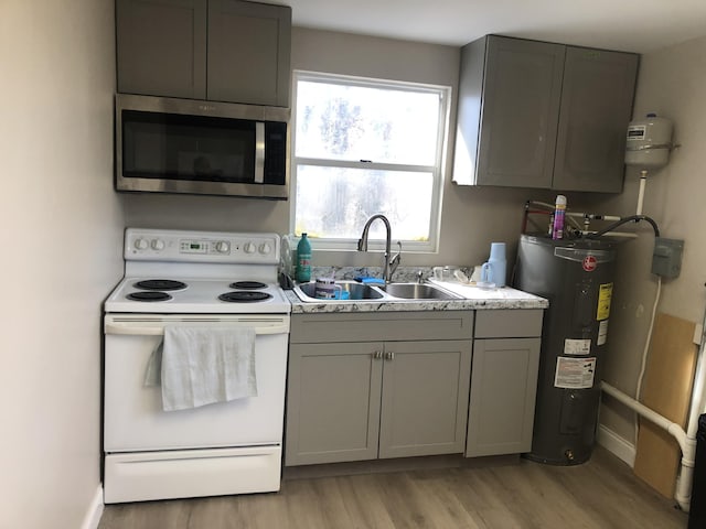 kitchen featuring gray cabinets, white electric range, stainless steel microwave, a sink, and electric water heater