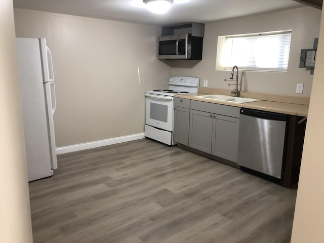 kitchen with light wood-style flooring, a sink, appliances with stainless steel finishes, light countertops, and baseboards