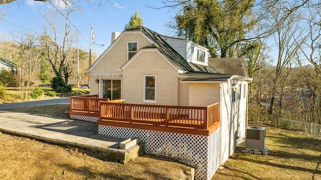 back of house featuring brick siding, central air condition unit, a wooden deck, and fence