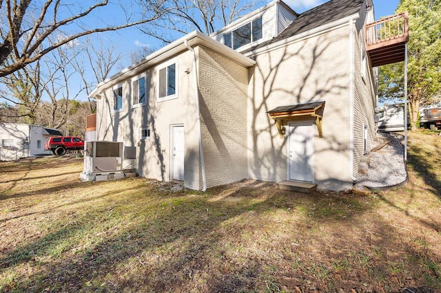 rear view of house featuring a lawn and brick siding