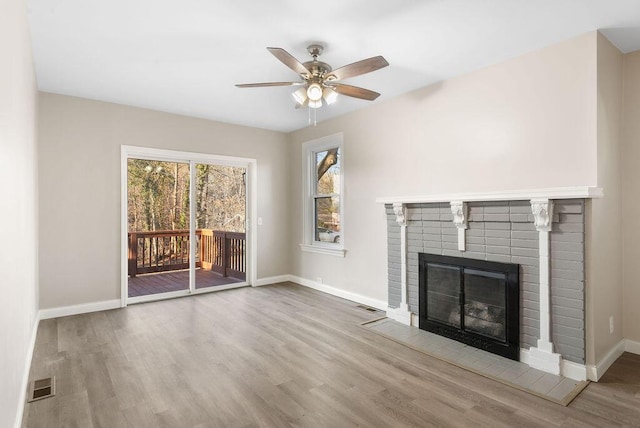 unfurnished living room featuring visible vents, a fireplace, baseboards, and wood finished floors