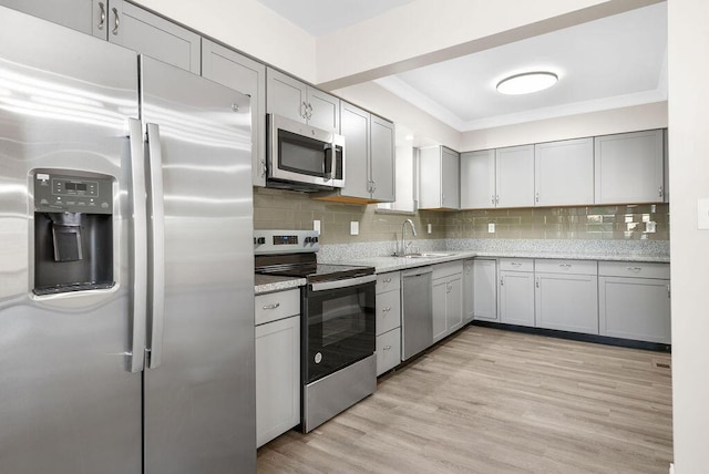 kitchen with a sink, tasteful backsplash, gray cabinets, and stainless steel appliances