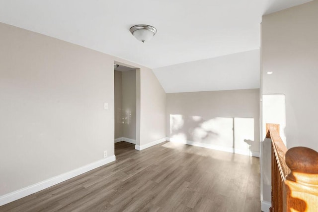 bonus room featuring baseboards, wood finished floors, and vaulted ceiling