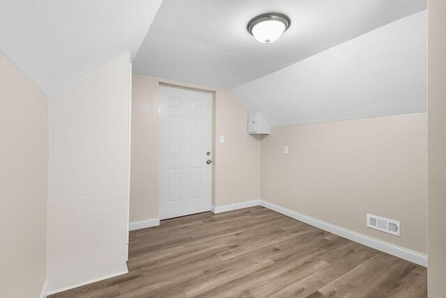 bonus room with visible vents, baseboards, lofted ceiling, and wood finished floors