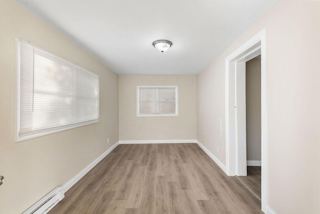 unfurnished room featuring light wood finished floors, baseboard heating, and baseboards