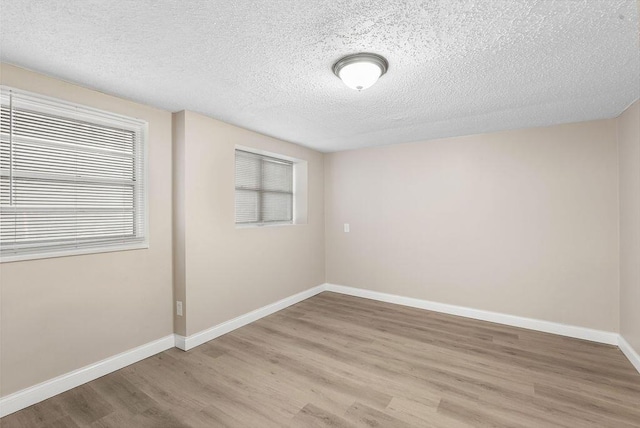 unfurnished room with baseboards, a textured ceiling, and light wood-style flooring