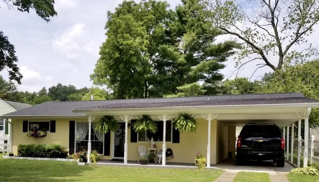 ranch-style house with a shingled roof, a front lawn, an attached carport, and stucco siding