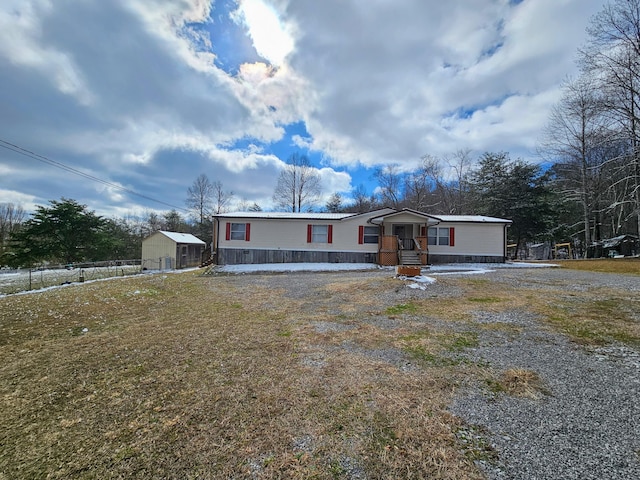 manufactured / mobile home with driveway, a storage shed, and a front yard