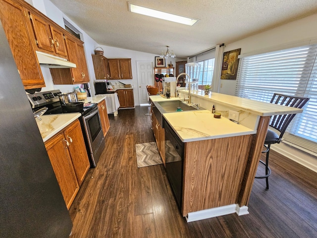 kitchen featuring a center island with sink, stainless steel electric range oven, light countertops, under cabinet range hood, and a sink