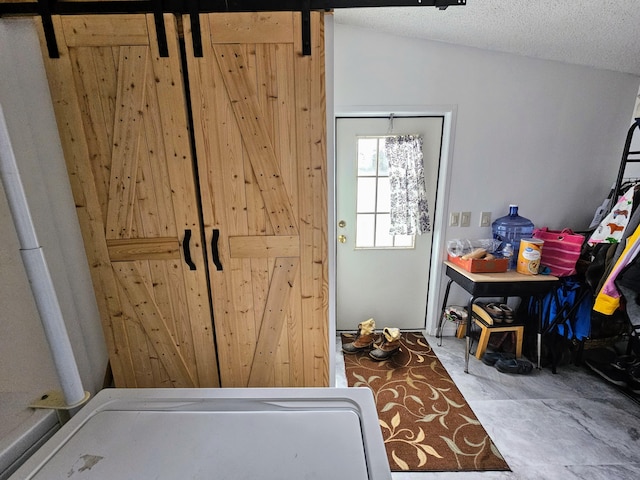 doorway featuring lofted ceiling, a textured ceiling, and a barn door