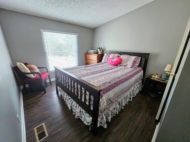 bedroom featuring a textured ceiling, dark wood-type flooring, visible vents, and baseboards