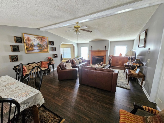 living room with arched walkways, dark wood-type flooring, vaulted ceiling with beams, and a healthy amount of sunlight