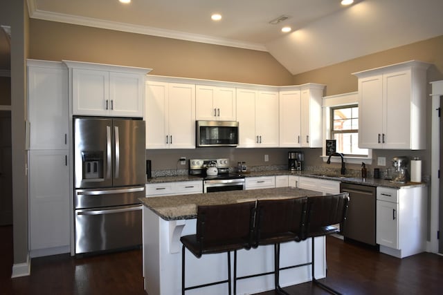 kitchen with white cabinets, a center island, stainless steel appliances, a kitchen bar, and a sink