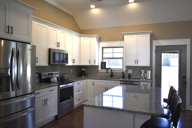 kitchen featuring white cabinets, appliances with stainless steel finishes, a breakfast bar, a center island, and a sink