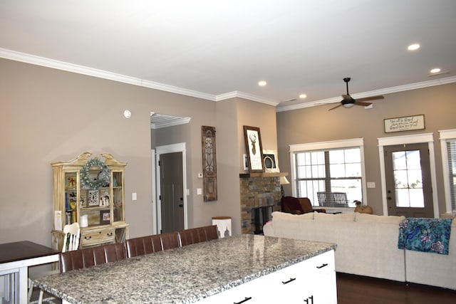 kitchen with open floor plan, a breakfast bar, white cabinetry, and light stone countertops