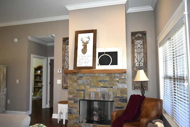 living room featuring dark wood-type flooring, crown molding, a stone fireplace, and baseboards