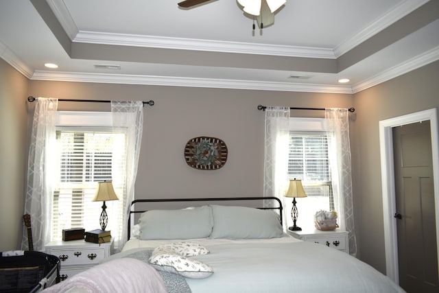 bedroom with ceiling fan, visible vents, a raised ceiling, and crown molding