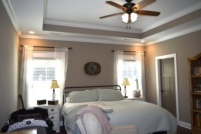 bedroom with ornamental molding, a tray ceiling, visible vents, and ceiling fan