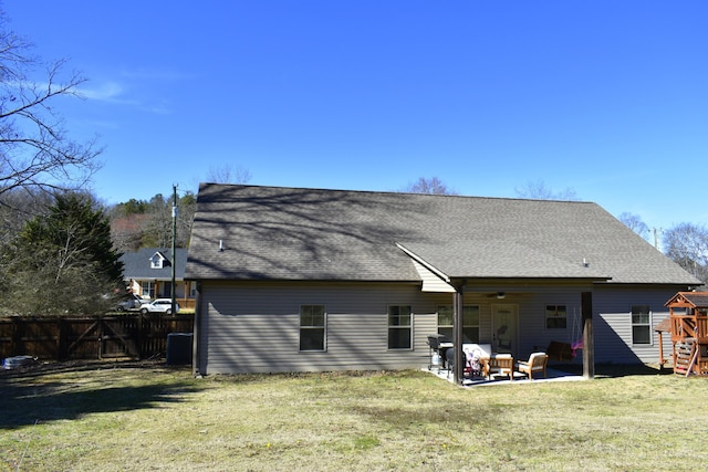 back of property featuring a shingled roof, fence, a yard, a patio area, and a playground