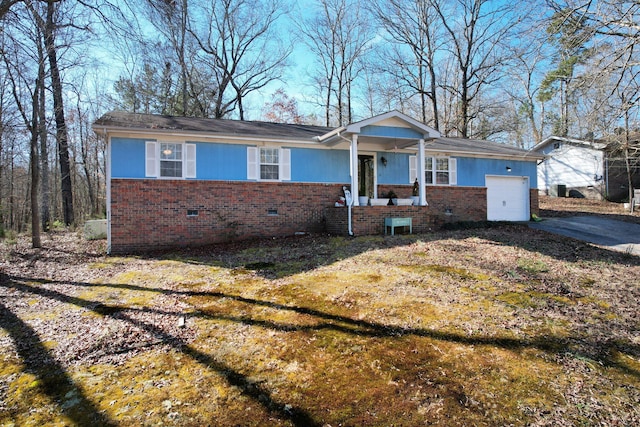 ranch-style house with brick siding, an attached garage, a front yard, crawl space, and driveway