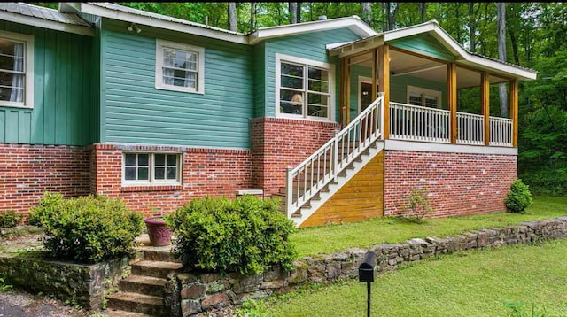 view of front of house with a porch, brick siding, metal roof, and stairs