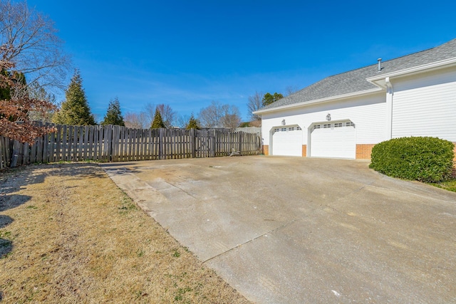 exterior space featuring driveway, brick siding, and fence