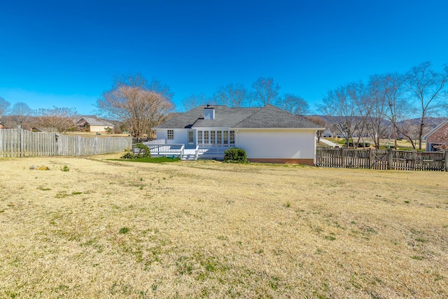 rear view of property with a deck, a yard, and a fenced backyard