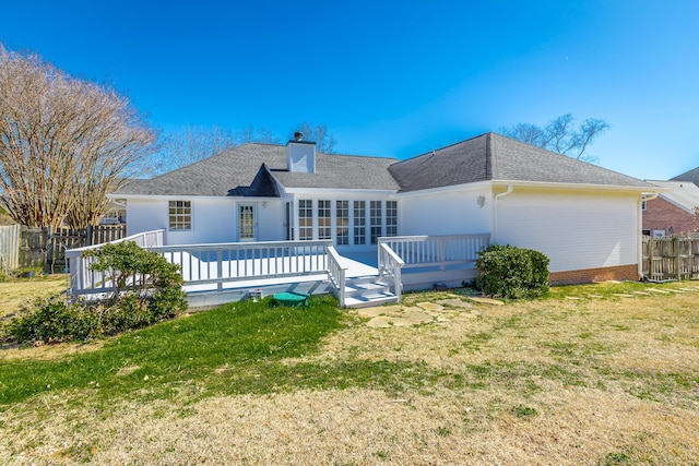 rear view of house featuring a deck, a lawn, a chimney, and fence