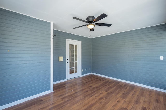 unfurnished room featuring dark wood-style flooring, a ceiling fan, and baseboards