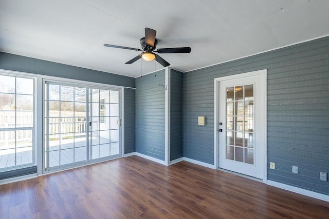 spare room featuring dark wood-style flooring, a ceiling fan, and baseboards