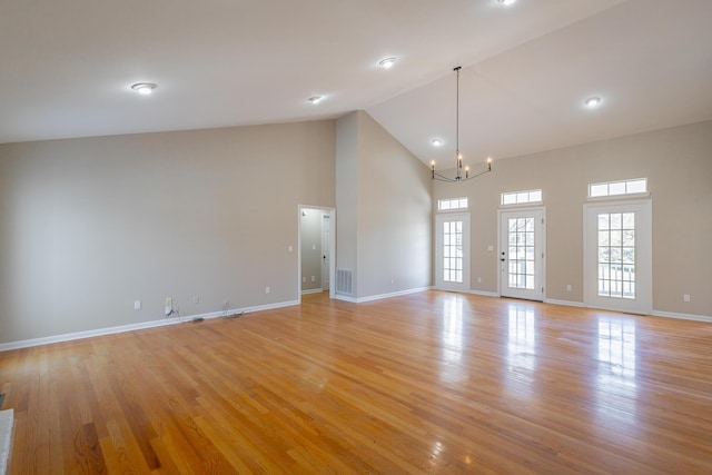 empty room featuring visible vents, baseboards, light wood-style floors, high vaulted ceiling, and a notable chandelier