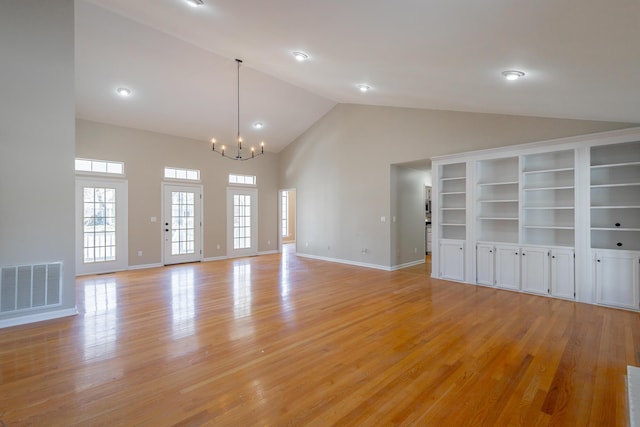 unfurnished living room with baseboards, light wood-type flooring, visible vents, and a notable chandelier