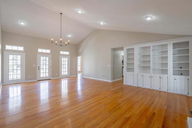 unfurnished living room featuring baseboards, high vaulted ceiling, light wood-type flooring, and a notable chandelier