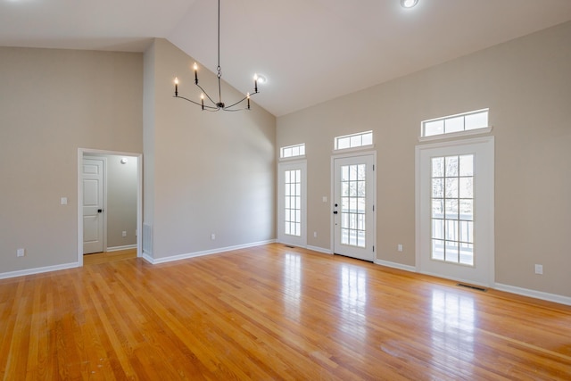 spare room with light wood-style floors, a chandelier, visible vents, and baseboards