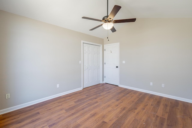 empty room with a ceiling fan, vaulted ceiling, baseboards, and wood finished floors