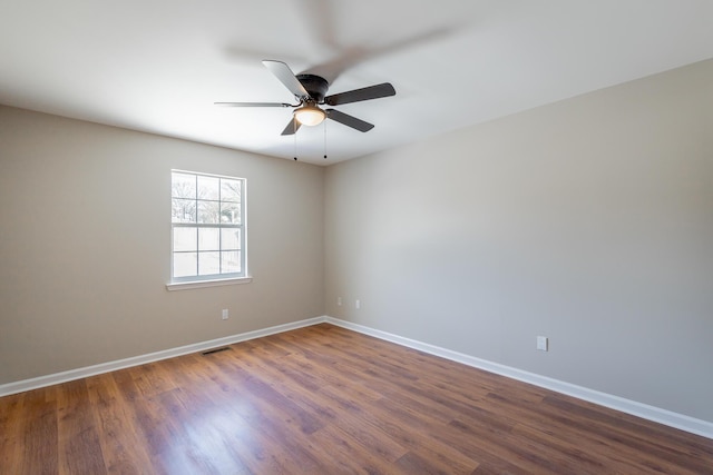 spare room featuring dark wood-style flooring, visible vents, ceiling fan, and baseboards