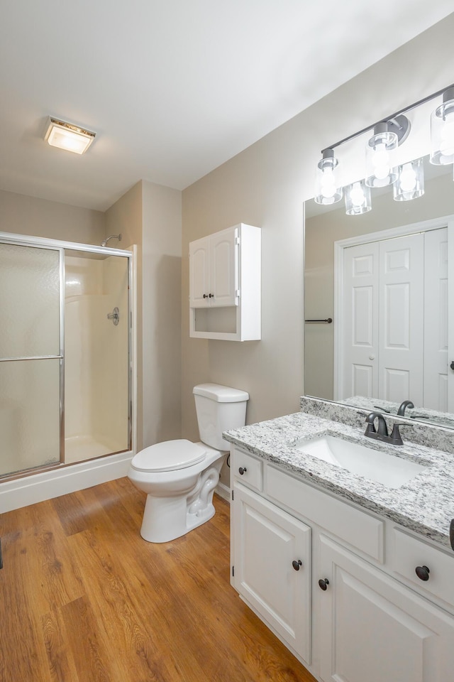 full bath featuring toilet, wood finished floors, a shower stall, and vanity