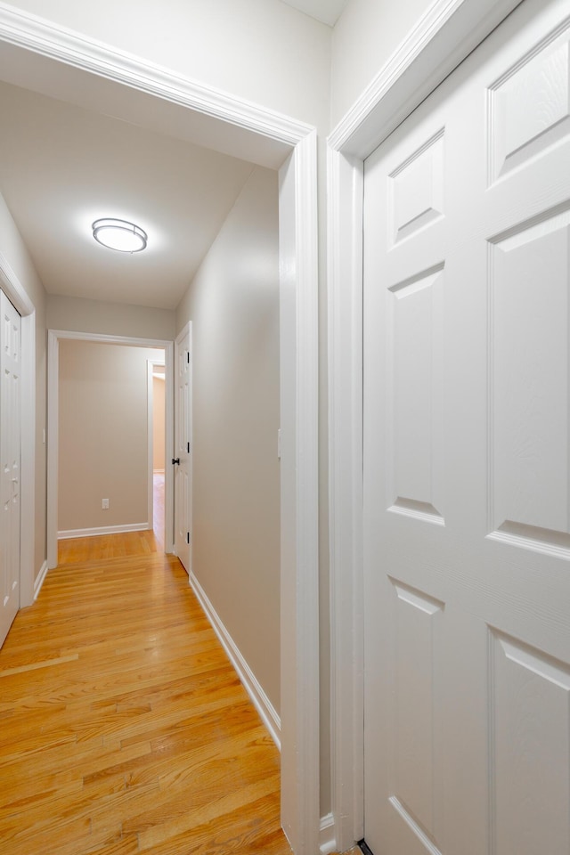 hallway featuring light wood finished floors and baseboards