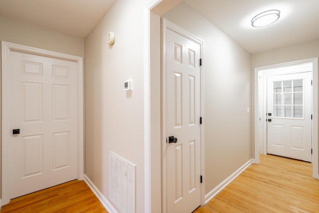 hallway featuring light wood-style flooring, visible vents, and baseboards