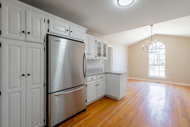 kitchen with lofted ceiling, white cabinetry, light wood-type flooring, freestanding refrigerator, and glass insert cabinets