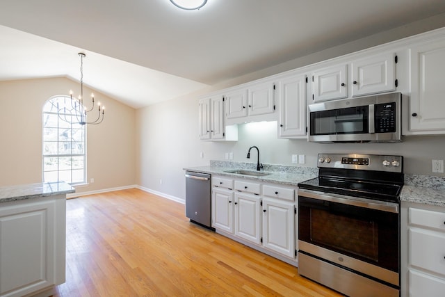 kitchen with lofted ceiling, a sink, white cabinets, light wood-style floors, and appliances with stainless steel finishes