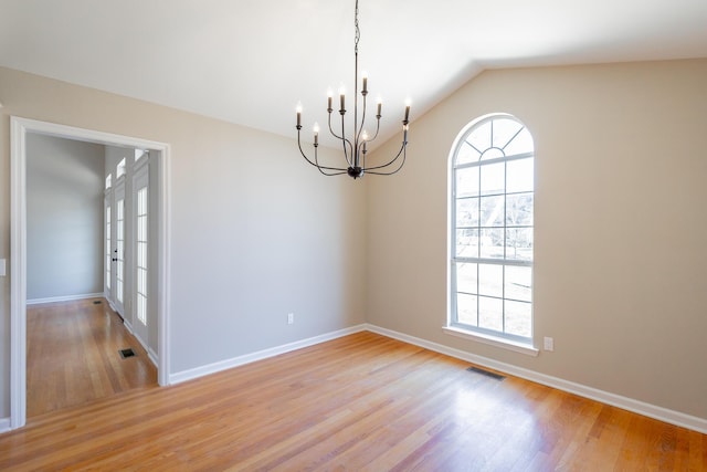 spare room with lofted ceiling, light wood-style floors, visible vents, and a healthy amount of sunlight