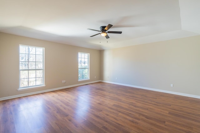 empty room featuring dark wood-style flooring, a ceiling fan, and baseboards