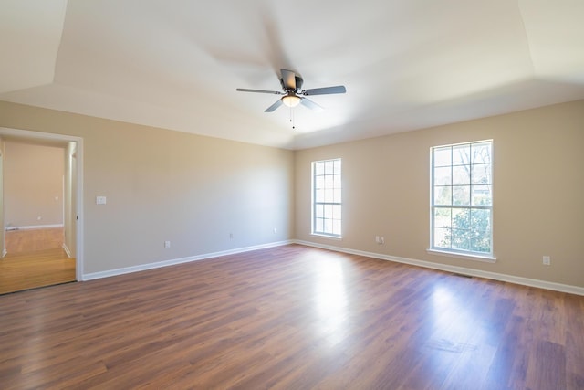 unfurnished room with dark wood finished floors, a ceiling fan, and baseboards